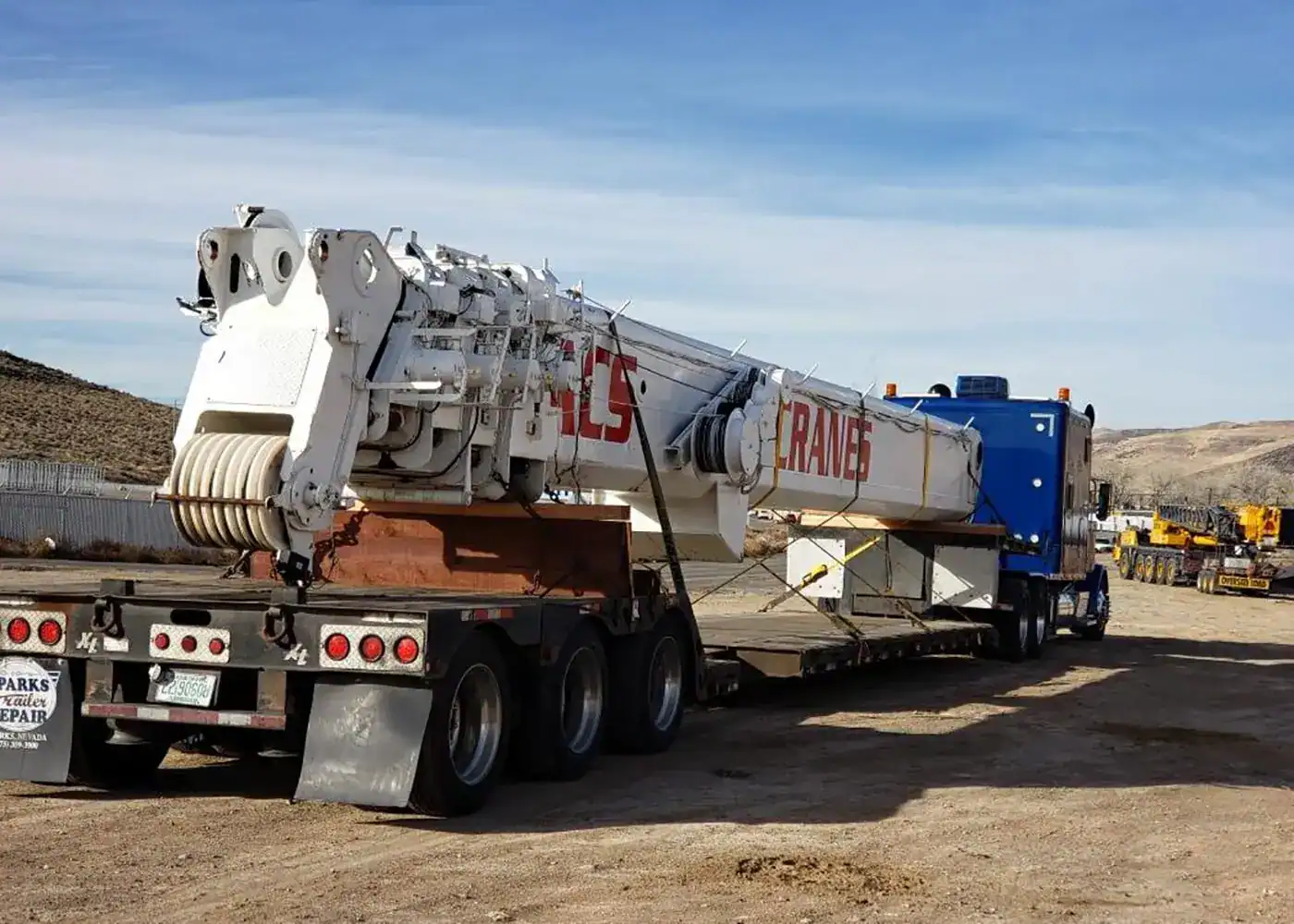 White crane on trailer in desert yard.