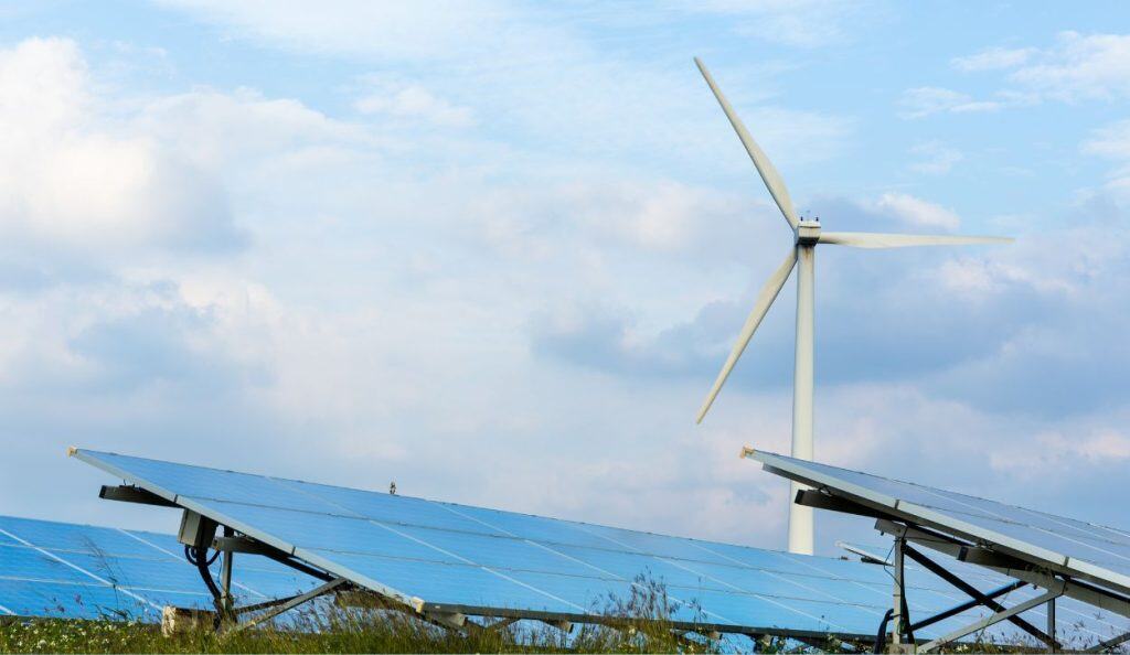 Photo showing wind turbine behind rows of solar panels
