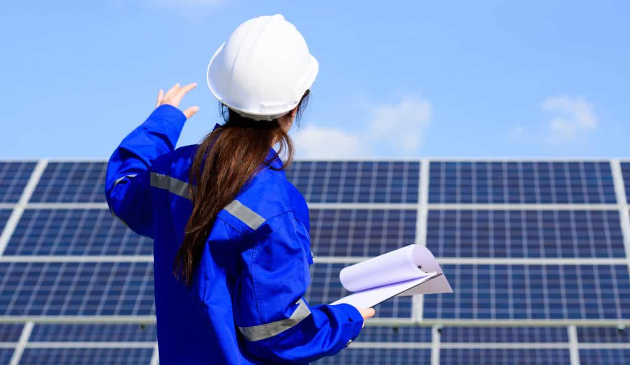 Solar project engineer surveying rows of solar panels