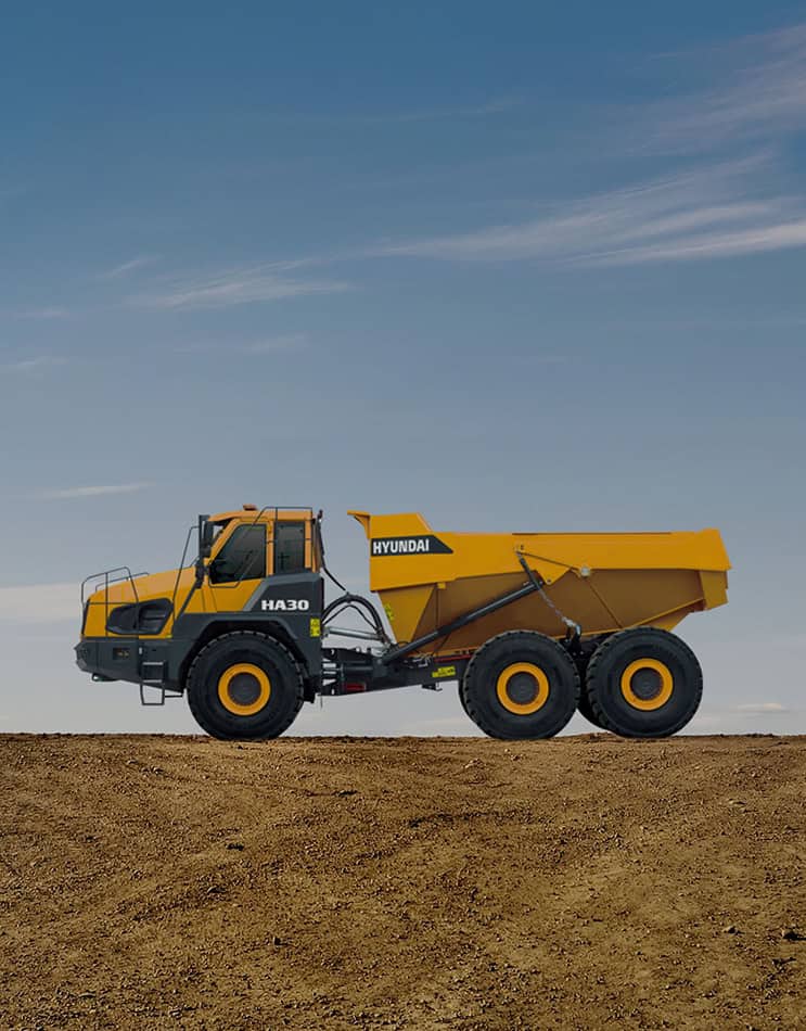 Large yellow Hyundai HA30 articulated dump truck on a dirt construction site against a clear blue sky.
