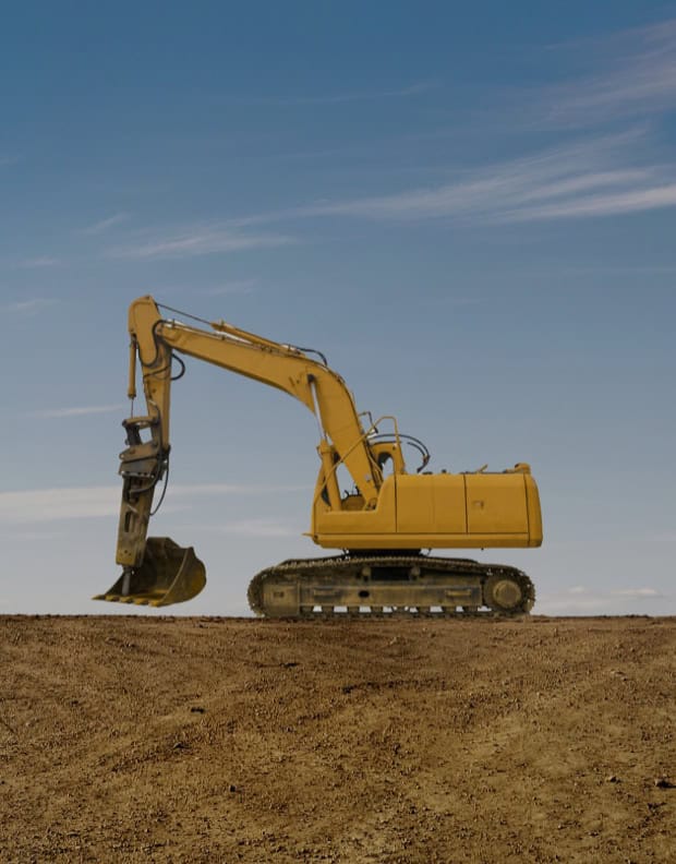Yellow excavator on a construction site under a clear blue sky.