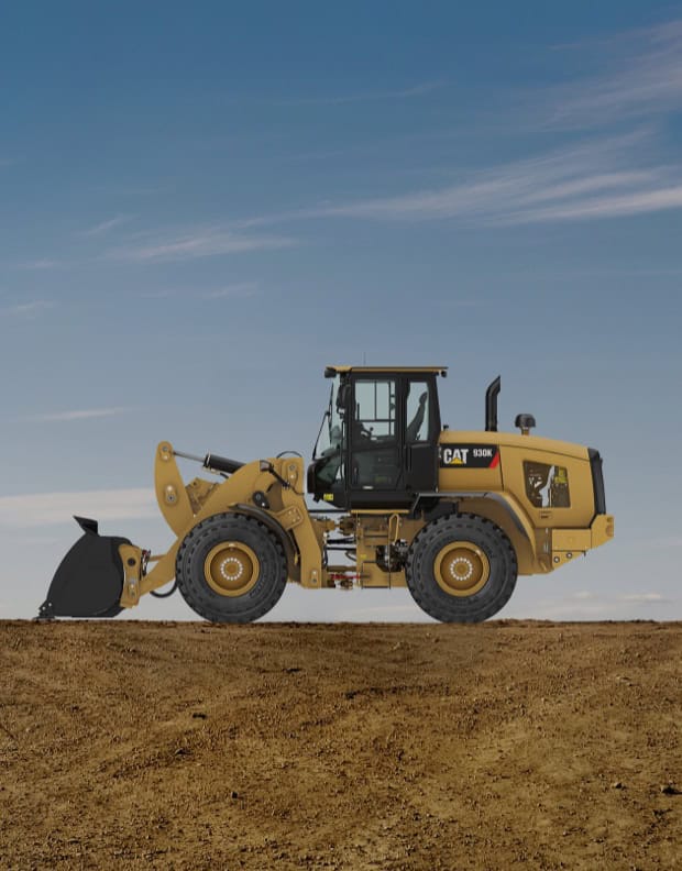 Yellow CAT 930K wheel loader on dirt with blue sky background.
