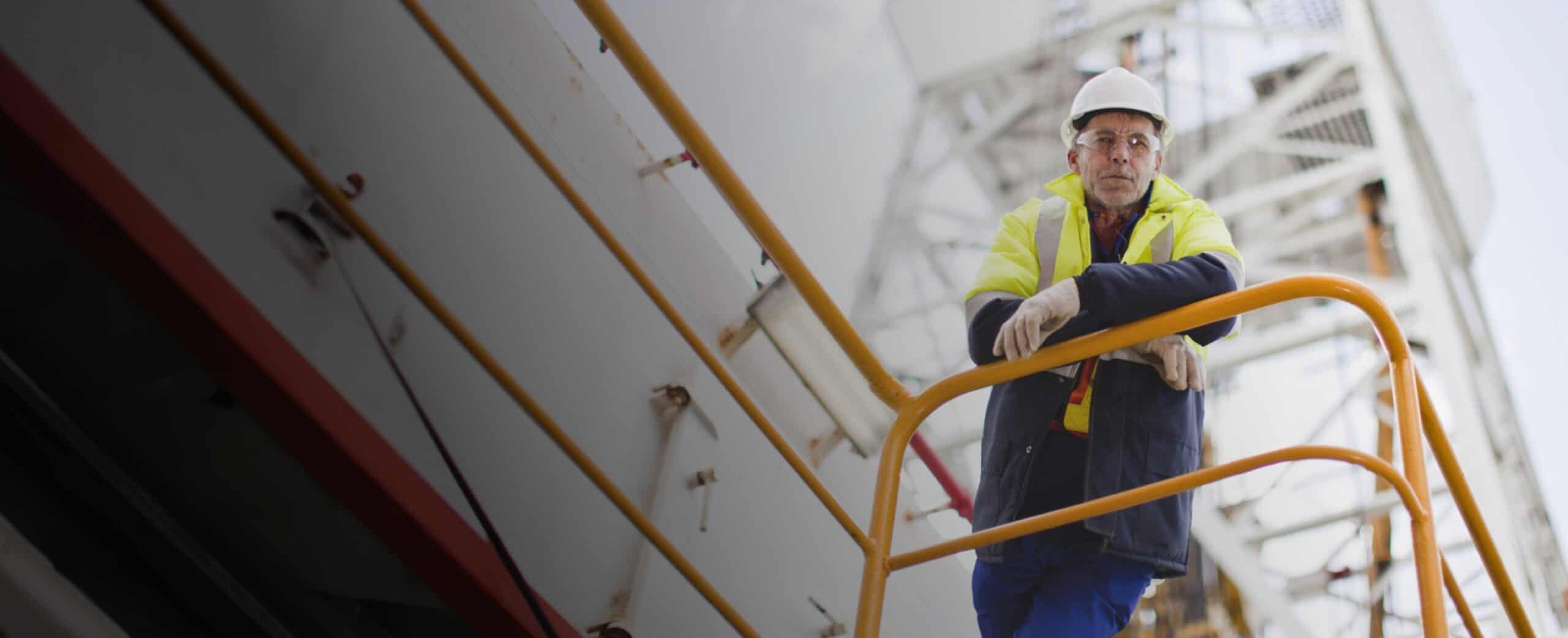Construction worker in protective gear standing on an industrial platform.