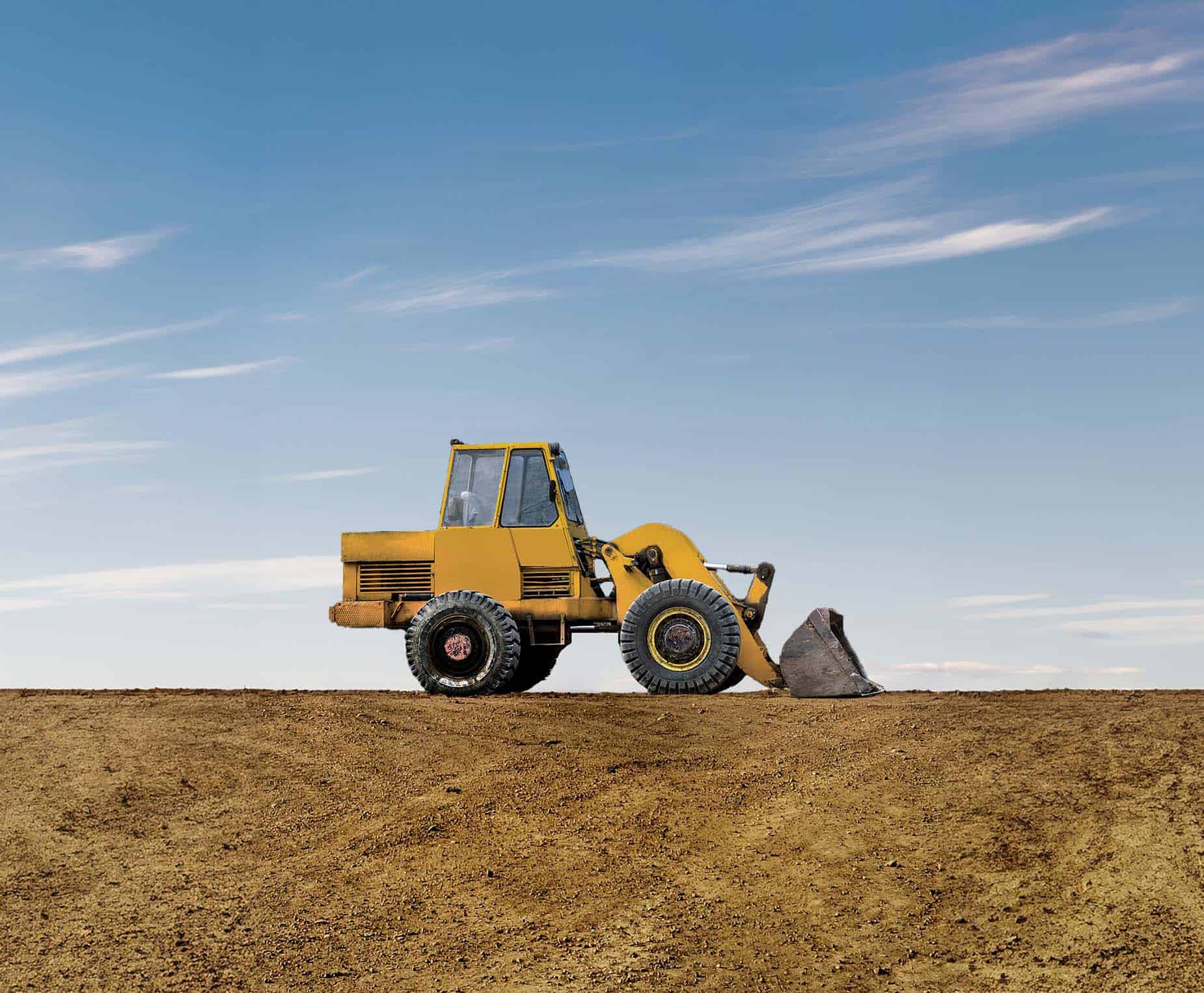 Yellow bulldozer on a construction site with clear blue sky.
