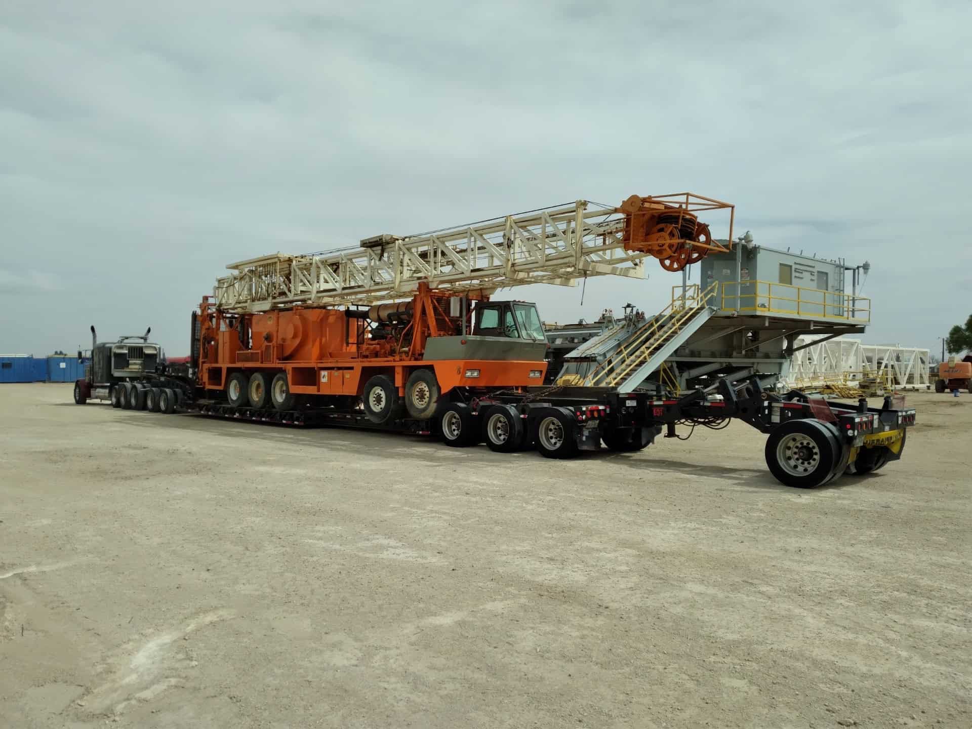 Orange crane on trailer at industrial yard.