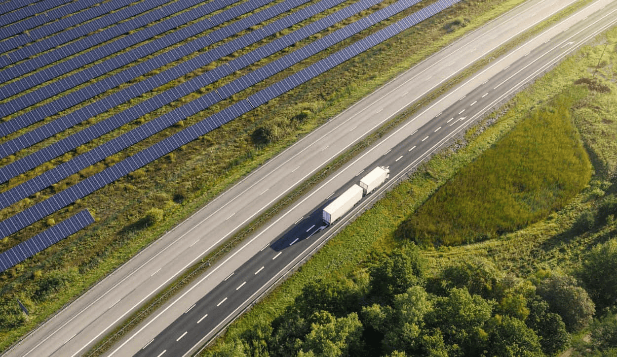Truck driving past solar panels on highway aerial