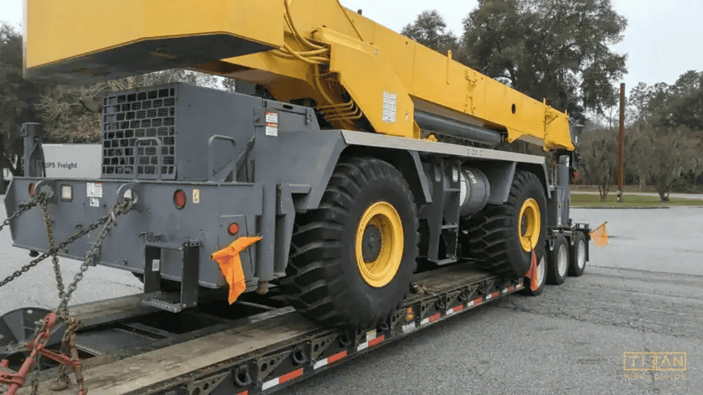 Yellow crane secured on flatbed truck for transport