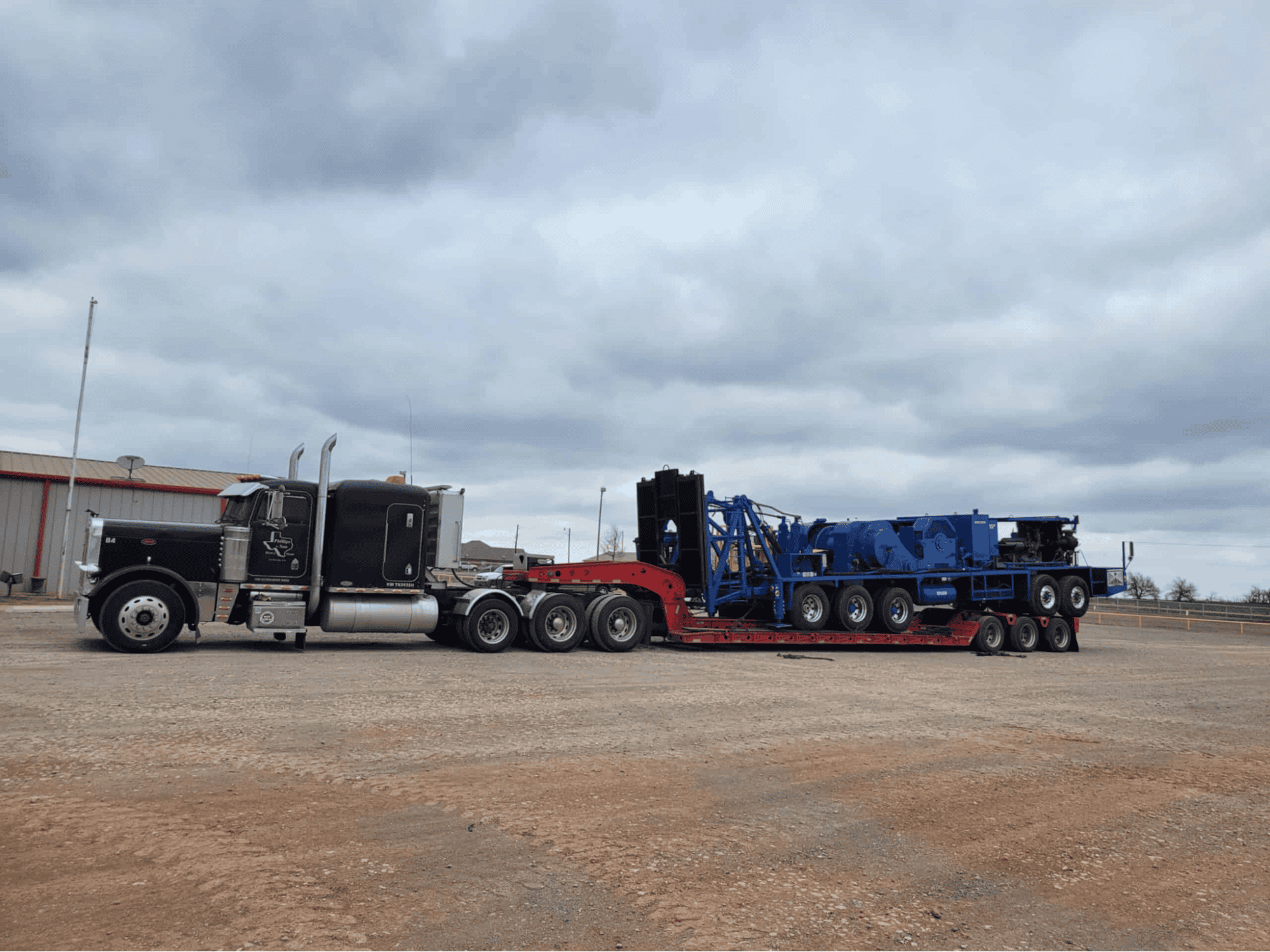 Heavy equipment transport truck hauling blue industrial machinery