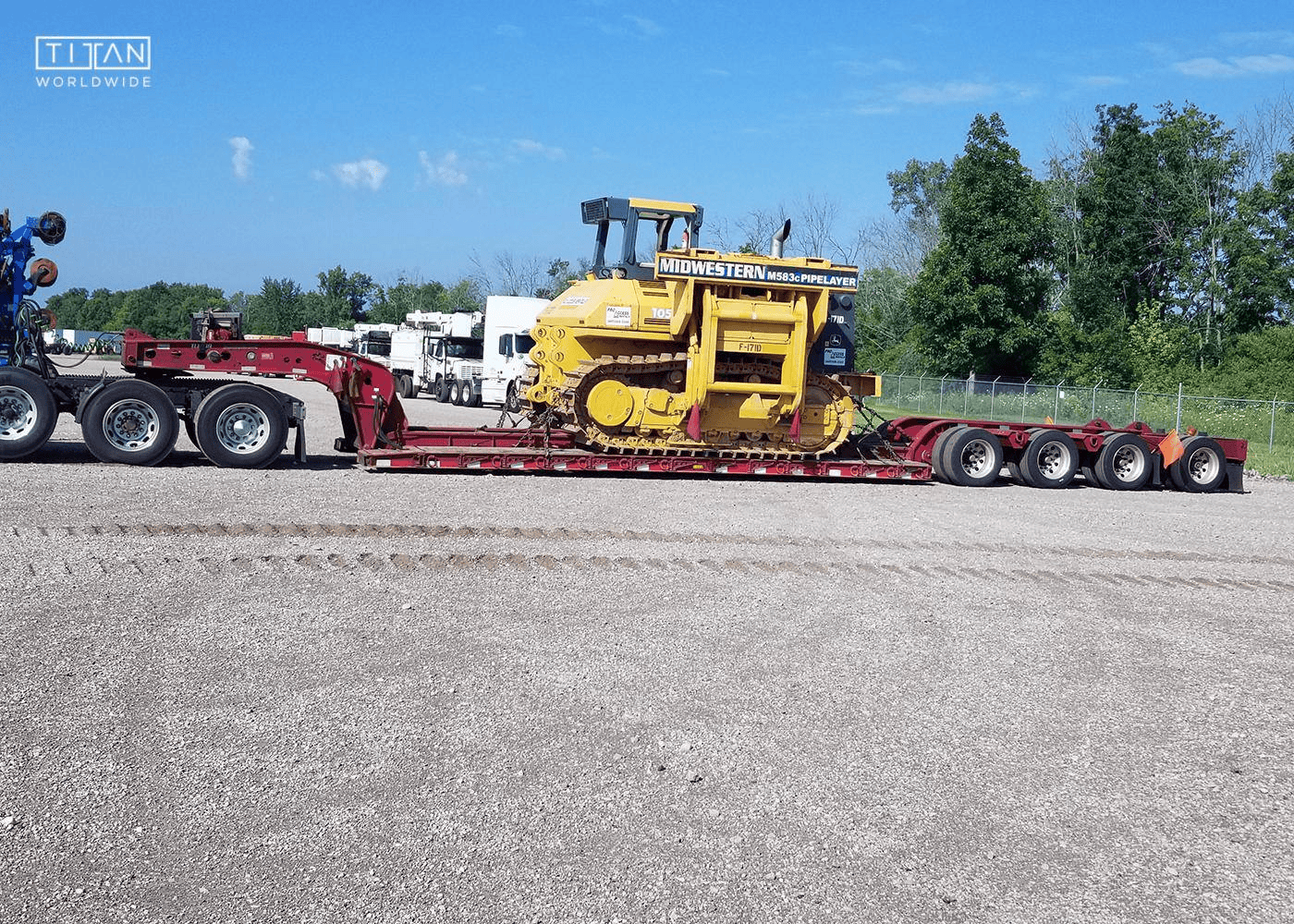 Yellow Caterpillar material handler loaded on transport trailer.