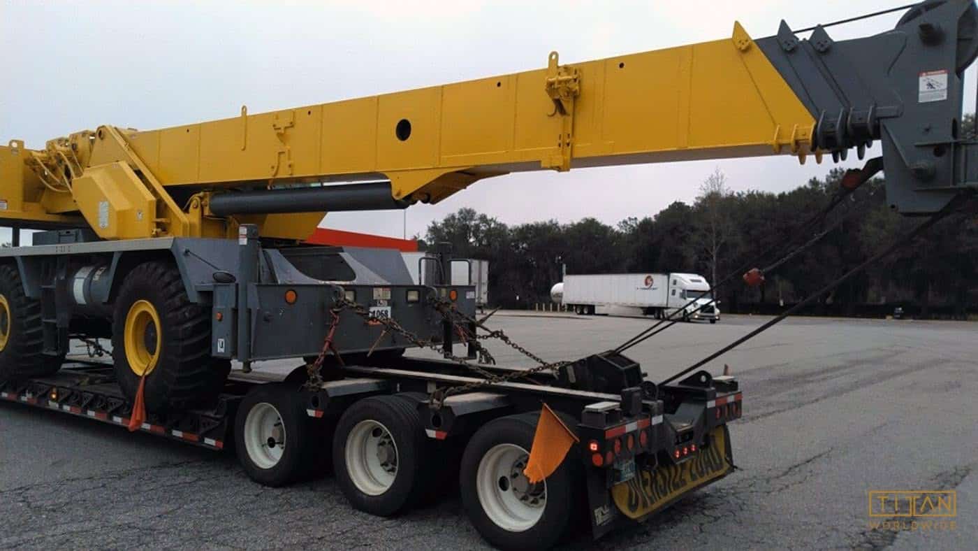Yellow crane on trailer secured with chains.