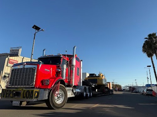 Red semi truck hauling Caterpillar 330 Hydraulic Excavator.