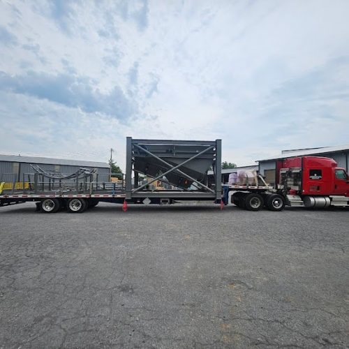 Red semi truck transporting large steel frame structure.